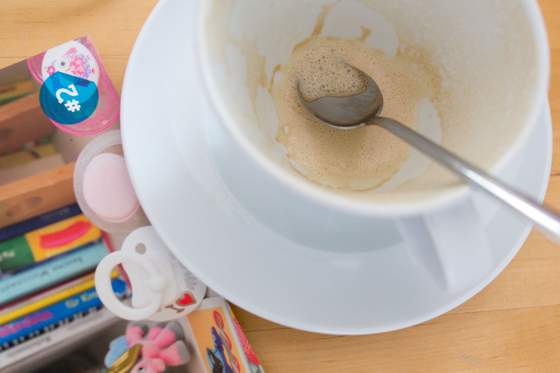 Leere Kaffeetasse, daneben liegen Schnuller und eine Broschüre